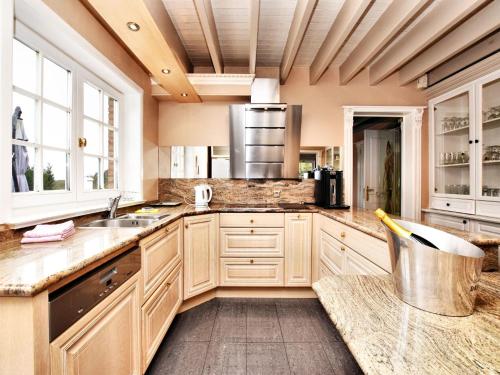 a large kitchen with wooden cabinets and a sink at Durbuy Luxe Villa with Pool in Petite Somme