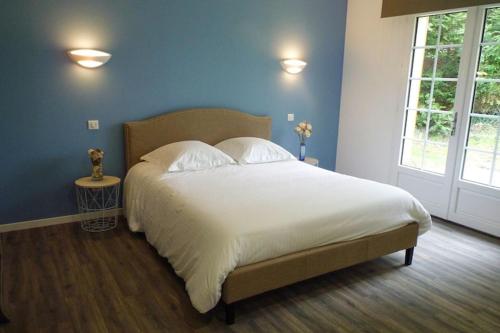 a bedroom with a large white bed with blue walls at Semi-detached house, Rieux in Rieux