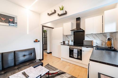 a kitchen and living room with a black leather couch at One Bed Room Apartment in Aberdeen City Centre Home Away From Home in Aberdeen