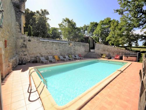 an outdoor swimming pool with chairs and a stone wall at Castle 12th century with private pool close to Agen in Saint-Caprais-de-Lerm