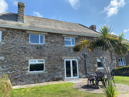 a brick house with tables and chairs in front of it at WALK TO THE BEACH, spacious cottage with sea views in St Merryn