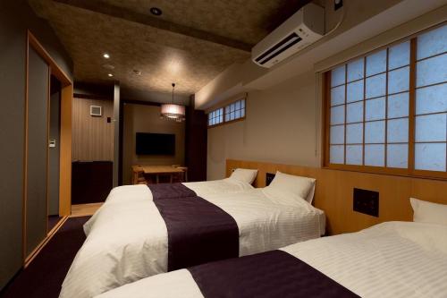 a hotel room with two beds and a television at Hotel Matsunoi Shurin in Tokyo