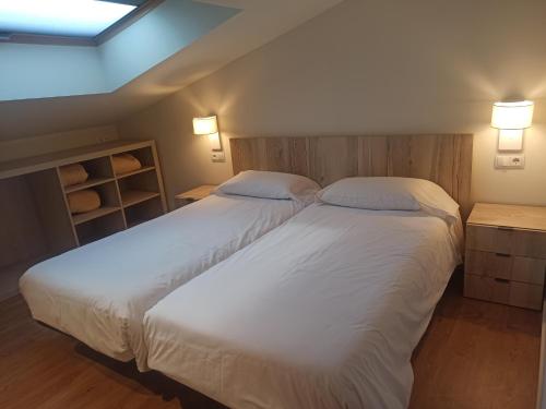 a bedroom with two beds with white sheets and lights at Apartament FREIXE de Molló Parc in Molló