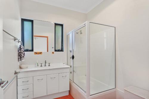a white bathroom with a shower and a sink at Straddie Hideout - Sleeps 9 - Pet Friendly in Point Lookout