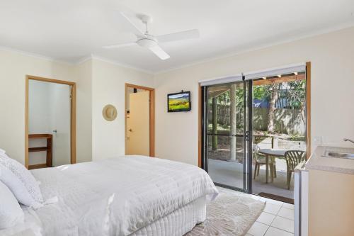 a bedroom with a bed and a patio with a table at Straddie Hideout - Sleeps 9 - Pet Friendly in Point Lookout