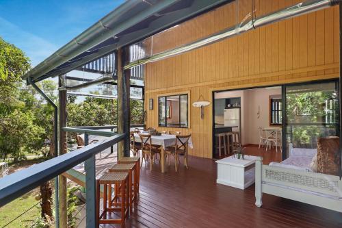 a house with a deck with a table and chairs at Straddie Hideout - Sleeps 9 - Pet Friendly in Point Lookout
