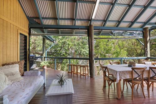a porch with a couch and a table and chairs at Straddie Hideout - Sleeps 9 - Pet Friendly in Point Lookout