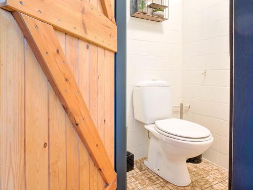 a bathroom with a toilet and a wooden door at Chalet in Ulestraten near Maastricht in Ulestraten
