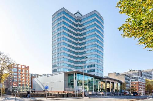 a tall glass building in a city at Holland House Hotel Cardiff By Sunday in Cardiff