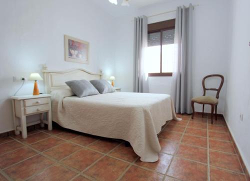 a bedroom with a bed and a chair and a window at Casa Rocio 1 in Conil de la Frontera