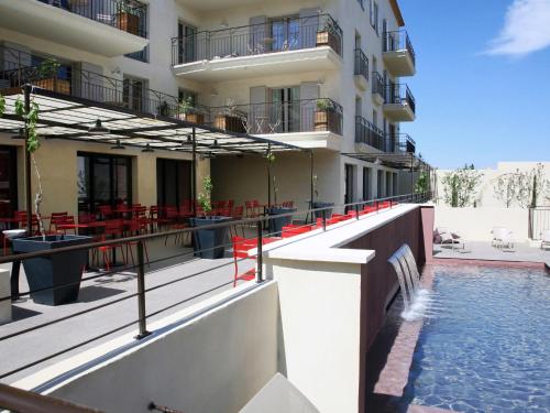 un hôtel avec une piscine en face d'un bâtiment dans l'établissement Garrigae Distillerie de Pezenas - Hotellerie & Spa, à Pézenas