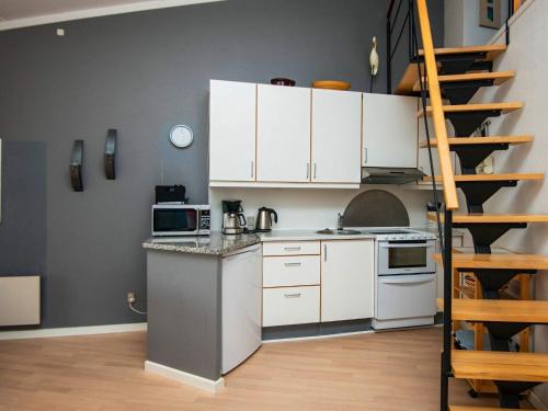 a kitchen with white cabinets and a spiral staircase at 6 person holiday home in Ringkøbing in Ringkøbing