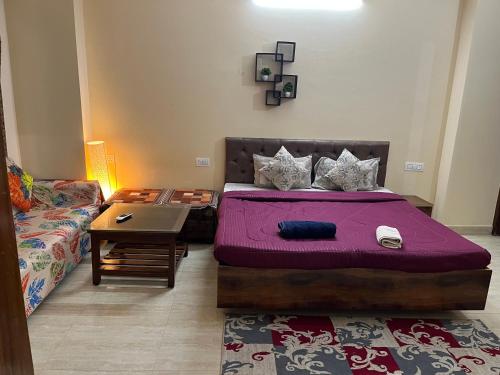 a bedroom with a bed and a table and a couch at Elite Heaven Retreat 1 BHK Budget Home Stay Tapovan in Tapovan