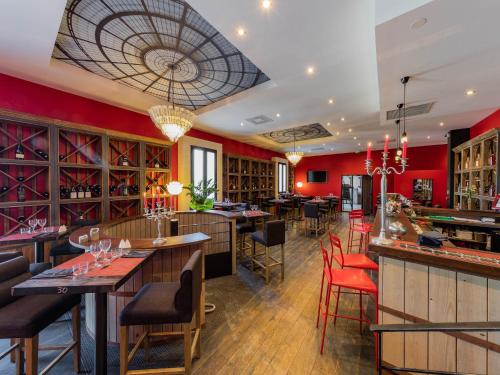 ein Restaurant mit roten Wänden und eine Bar mit Tischen und Stühlen in der Unterkunft Garrigae Distillerie de Pezenas - Hotellerie & Spa in Pézenas