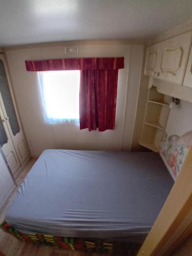 a bed in a small room with a window at logement caravane in Les Journeux