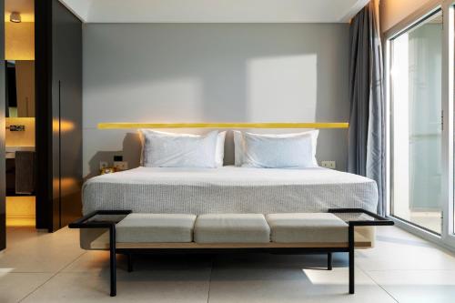 a bed with white pillows and a bench in a room at INNSiDE by Meliá Alicante Porta Maris in Alicante
