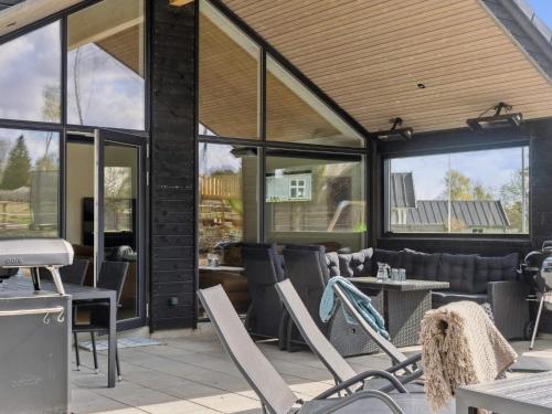 a patio with chairs and tables and windows at 5 star holiday home in Dronningmølle in Dronningmølle
