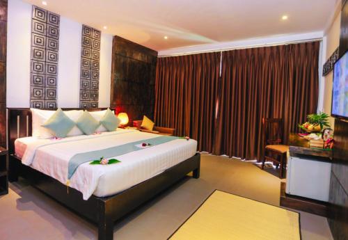 a bedroom with a large bed and a television at Angkor Land House in Phumĭ Réach Born