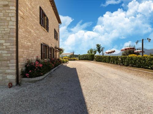a road next to a building with flowers on the side at Apartment in a farmhouse with 2 swimming pools in Cagli