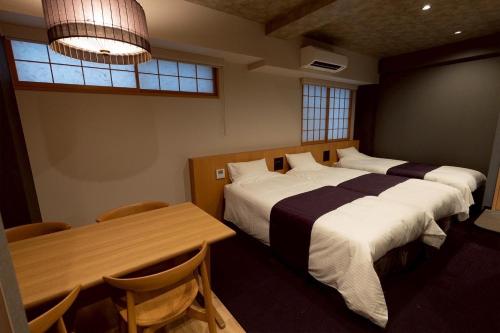 a bedroom with two beds and a table and chairs at Hotel Matsunoi Shurin in Tokyo