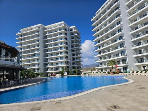 a large swimming pool in front of two large buildings at Sea View 2-Bedroom Apartment with Water Park at Caesar Blue Resort in Boğaz