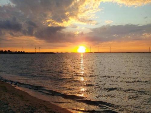 a sunset over a body of water with a beach at Luxury apartment in Résidence Marina Kamperland - pet friendly in Kamperland