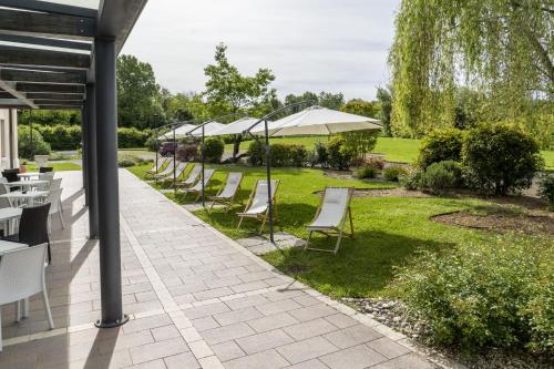 a patio with chairs and tables and umbrellas at Hotel Canova Sport & Relax in Cavaso del Tomba