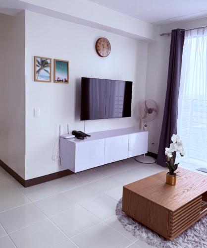 a white living room with a flat screen tv at Bright & Cozy High-Rise Condo in Pulong Cacawate