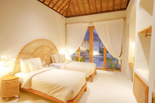a bedroom with two beds and a window at Aloha Boutique Uluwatu in Uluwatu