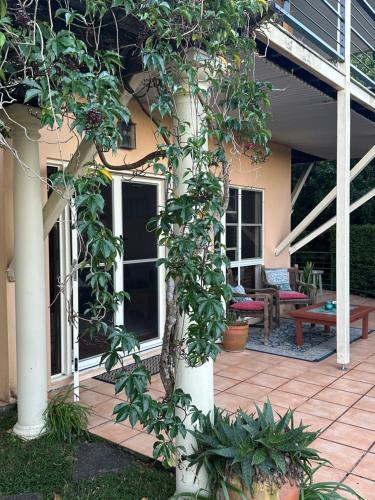 a patio with a tree and a bench on a house at River Rock Retreat in Maroochy River
