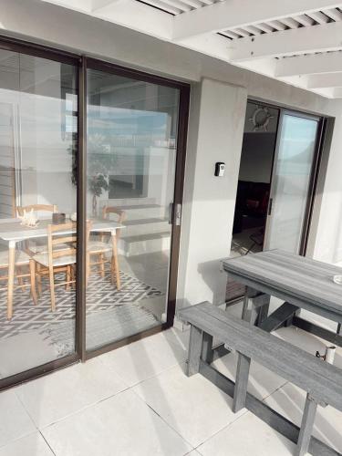 a patio with two benches and a table and a table and chairs at Black Pearl Harbour House in Gordonʼs Bay