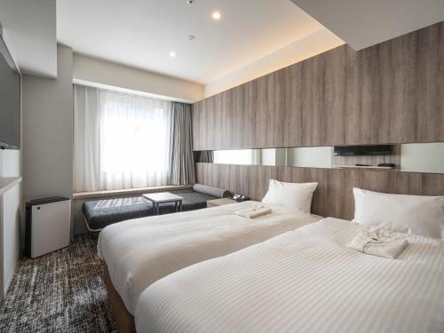 a hotel room with a large bed and a couch at Hotel Brighton City Osaka Kitahama in Osaka