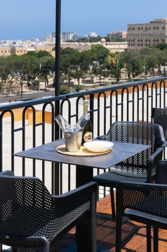 a table with a bottle of beer on a balcony at Florette Suite 1BR with Stunning Lounge Terrace by ArcoBnb in Il-Furjana
