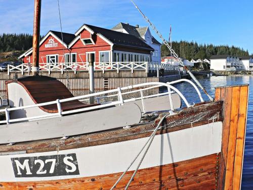 a boat is docked in front of a red house at 6 person holiday home in Austrheim in Utkeila
