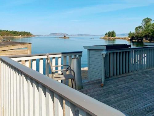 a deck with a table and a chair on the water at 6 person holiday home in Austrheim in Utkeila