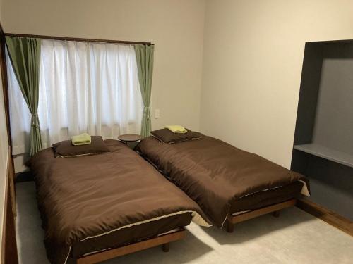 two beds in a room with a window at LT IZU Usami UMI in Ito