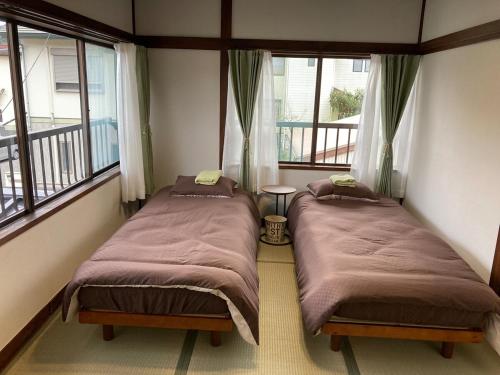 two beds sitting in a room with windows at LT IZU Usami UMI in Ito