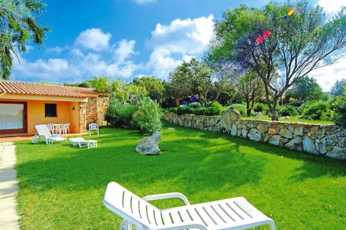 a yard with white benches and a stone wall at Apartment in Porto Pollo near Sea Beach in Porto Pollo