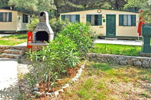 a garden with a brick oven in front of a house at Mobile Homes in Camp Kovacine, Cres, with long pebble beach in Cres