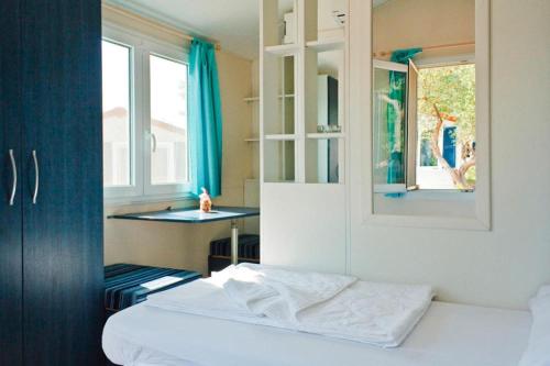 a bedroom with a bed and a table and window at Mobile Homes in Camp Kovacine, Cres, with long pebble beach in Cres