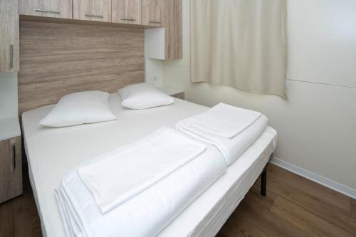 a white bed with two pillows on it in a room at Mobile Homes in Camp Kovacine, Cres, with long pebble beach in Cres