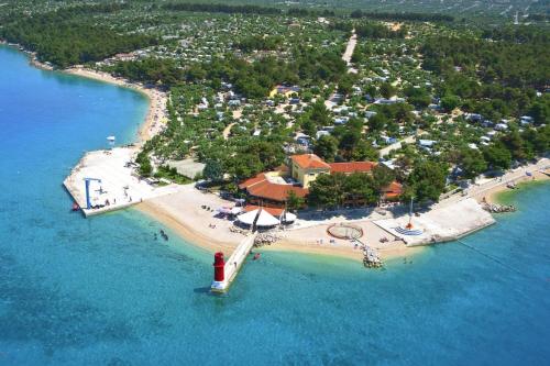 an island with a red lighthouse in the water at Mobile Homes in Camp Kovacine, Cres, with long pebble beach in Cres