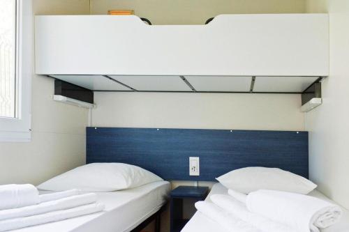 two beds in a room with white pillows at Mobile Homes in Camp Kovacine, Cres, with long pebble beach in Cres