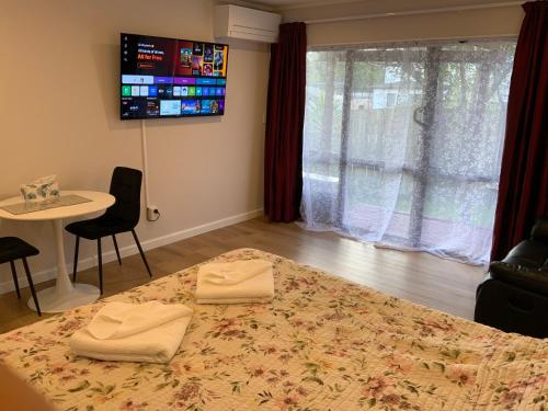 a bedroom with a bed and a table and a tv at Cascades Motor Lodge in Auckland