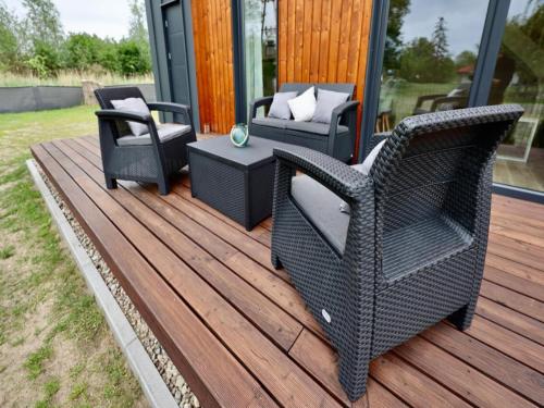 a deck with two wicker chairs and a table at Comfortable house by the beach in Stepnica in Stepnica