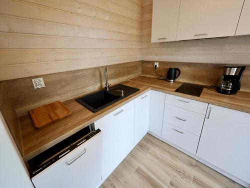 a small kitchen with white cabinets and a sink at Comfortable house by the beach in Stepnica in Stepnica