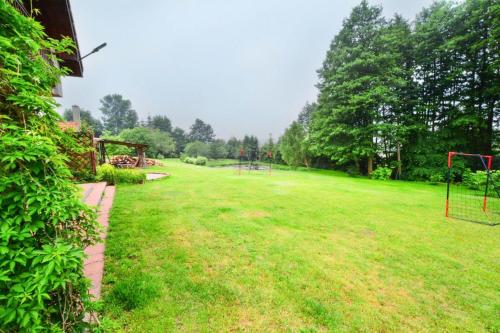 a large grassy yard with a playground at Comfortable holiday villa, Święcianowo in Zegocino