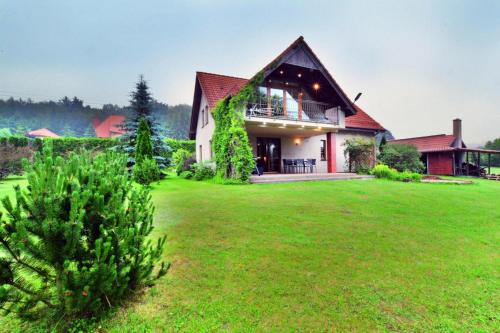 a house with a green lawn in front of it at Comfortable holiday villa, Święcianowo in Zegocino