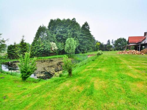 a grassy field with a river and a house at Comfortable holiday villa, Święcianowo in Zegocino