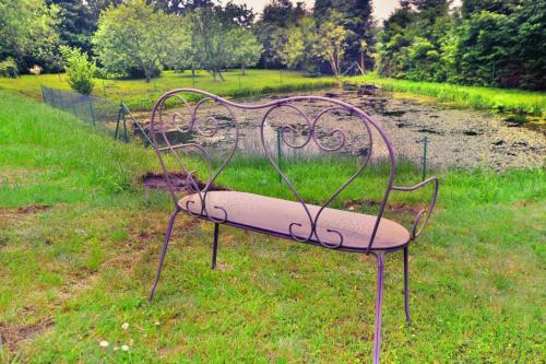 a metal bench sitting in the grass in a field at Comfortable holiday villa, Święcianowo in Zegocino